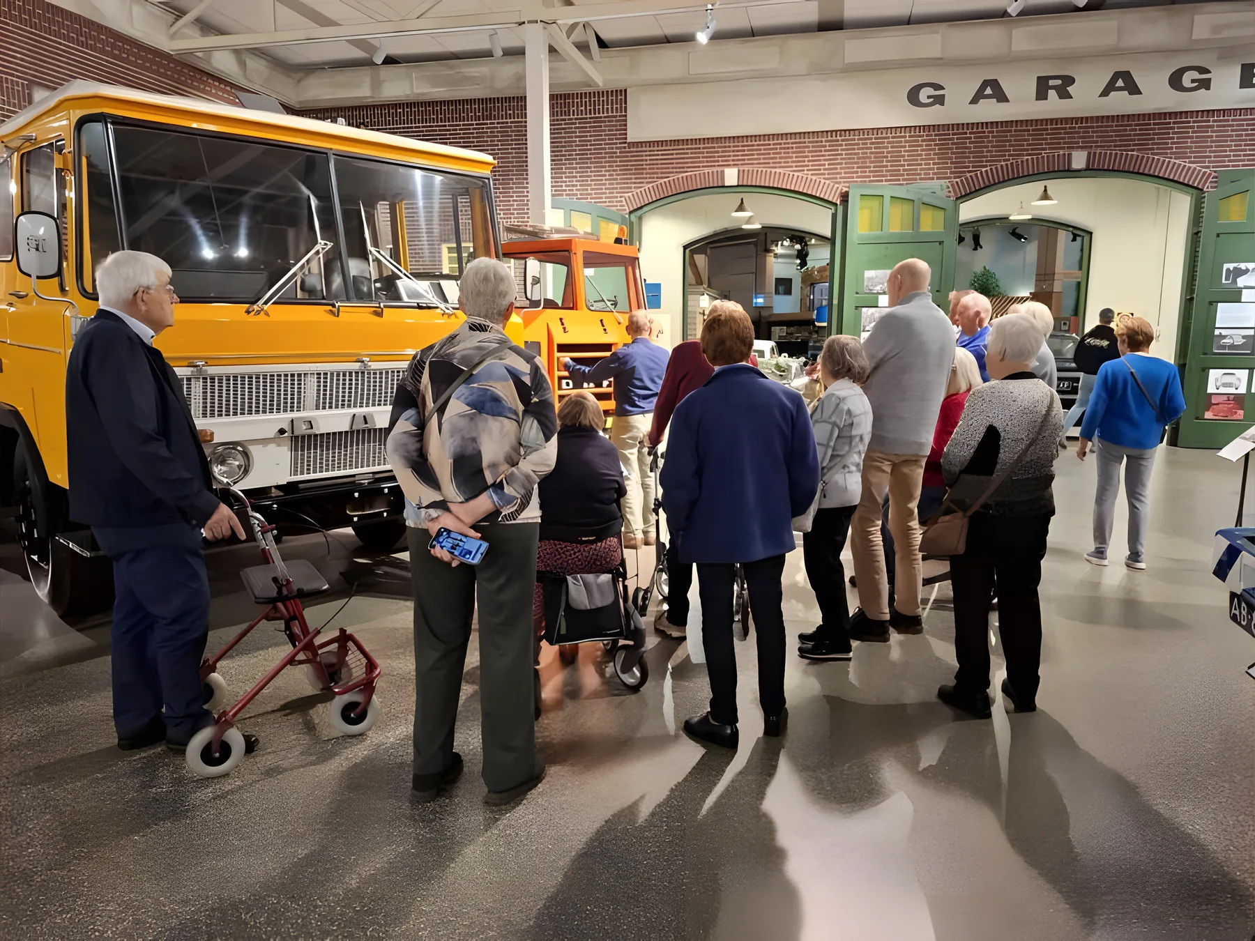 Gasten van de PlusBus met rollators bij een oude vrachtwagen in het DAF Museum