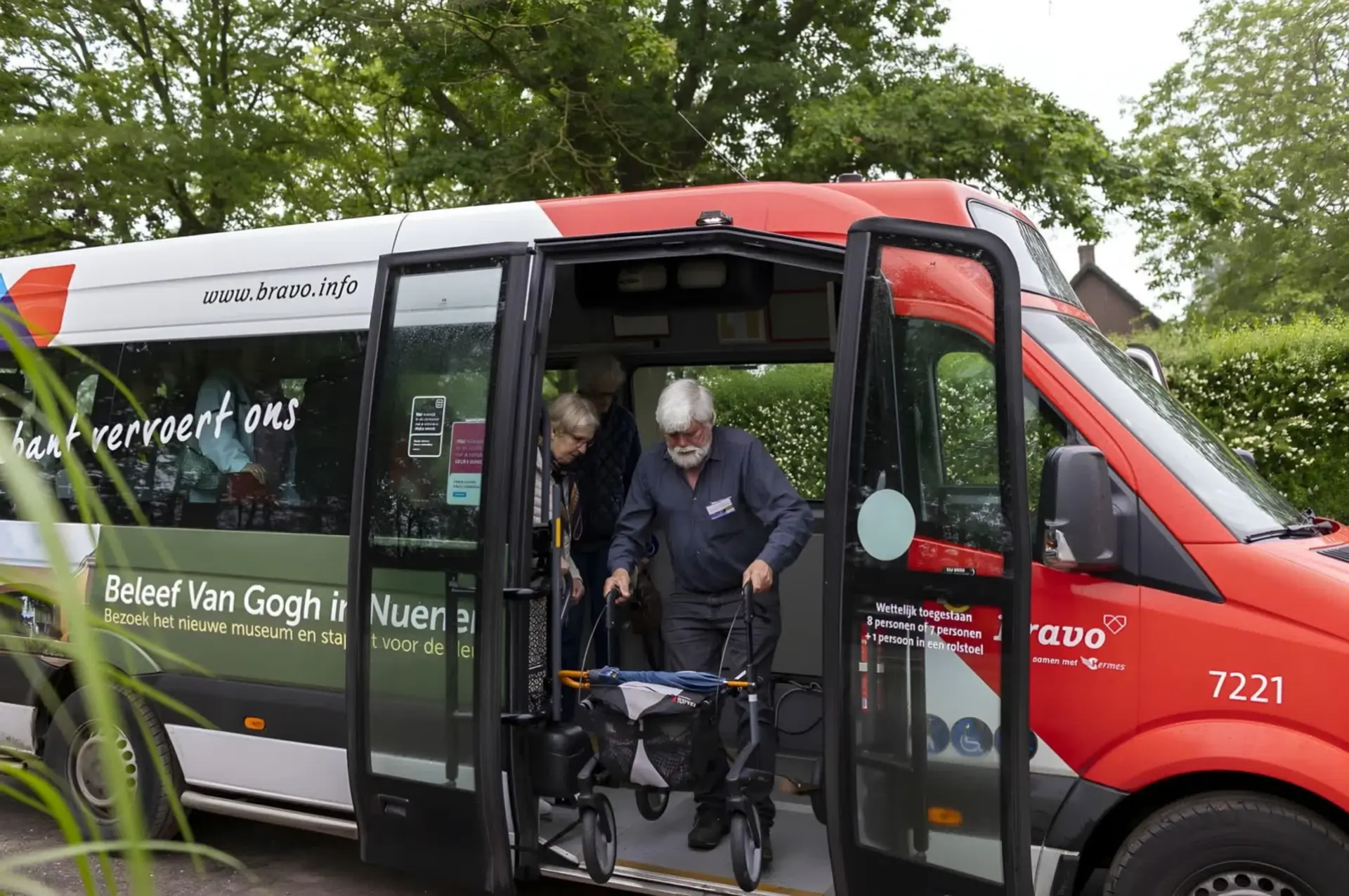 Een meneer met rollator stapt uit de PlusBus, een mevrouw volgt hem