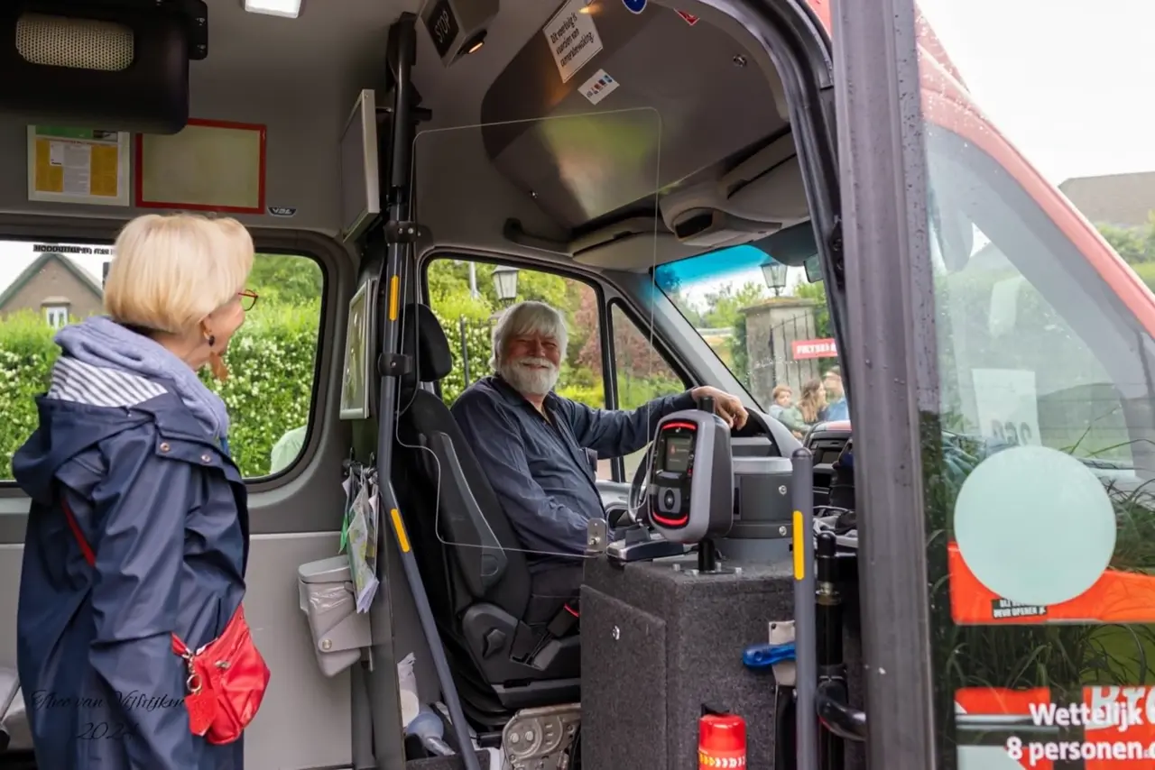 Een chauffeur van de PlusBus groet een mevrouw die instapt